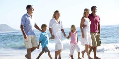 Three Generation Family Walking Along Sandy Beach